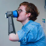 Mann hält Becher mit 3D-gedruckter Prothese