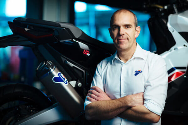 Marinelli steht mit den Armen verschränkt vor dem Motorrad