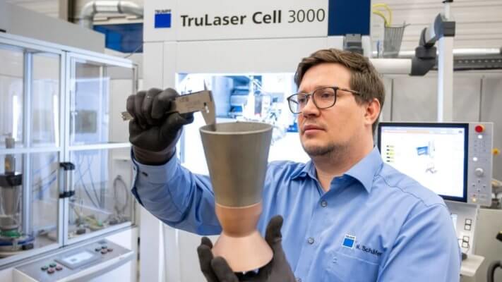 Mann hält Schubdüse und dahinter steht ein TruLaser Cell 3000