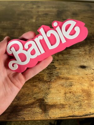 Barbie-Dekoschild in der Hand