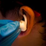 Proband trägt Ohrhörer, der Gehirnaktivität misst, entwickelt durch 3D-Drucktechnologie