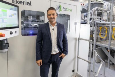 Eric Bader von ExOne vor Exerial Binderjet-3D-Drucker Geschäftsführer Eric Bader steht vor ExOne Binderjet-System in BMW Produktionsstätte.