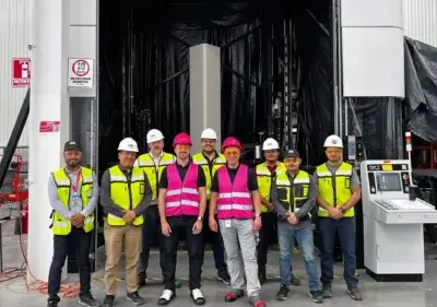 Mighty Buildings Team mit 3D-Drucker für den Bausektor Mitarbeiter von Mighty Buildings neben einem 3D-Drucker für den Bau