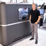 Nate Higgins neben einem X25 Pro 3D-Drucker von Desktop Metal