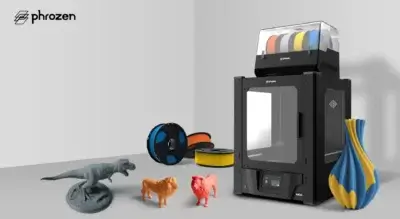 Phrozen Arco 3D-Drucker mit Multi-Filament-Druckkapazität und Beispielen für hochwertige Drucke Phrozen Arco FDM 3D-Drucker neben mehrfarbigen Filamenten und einer Auswahl an 3D-gedruckten Modellen