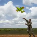 Air Force Offizier wirft eine leuchtend grüne Drohne, entwickelt in unter 24 Stunden durch 3D-Druck, in den Himmel