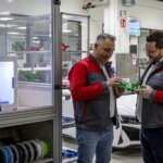Zwei Audi Sport Mitarbeiter betrachten 3D-gedruckte Werkzeuge neben einem Ultimaker S5 3D-Drucker