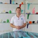 Mitarbeiter von 3D FilaPrint präsentiert 3D-gedruckte Objekte im Unternehmensstandort.