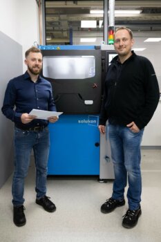 Peter Scherer und Josef Weissthanner von Rohde & Schwarz vor der neuen Solukon-Entpulverungsanlage im Werk Teisnach Peter Scherer, Head of Additive Manufacturing, und Josef Weissthanner, Technologe & Spezialist Additive Manufacturing, von Rohde & Schwarz vor der neuen Solukon-Entpulverungsanlage