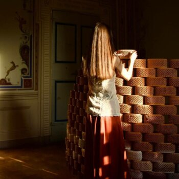 3D-gedruckte Keramikziegel in der Installation Future Archeologies 2049 bei Argillà 2024 Frau vor einer Wand aus 3D-gedruckten Keramikziegeln in der Installation Future Archeologies 2049