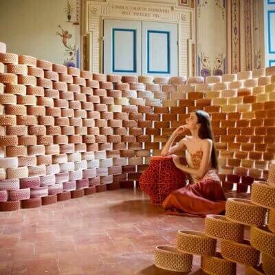 Installation Future Archeologies 2049 mit 3D-gedruckten Keramikziegeln bei Argillà 2024 Frau in einem Raum mit Wänden aus 3D-gedruckten Keramikziegeln, Installation Future Archeologies 2049