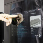 Nahaufnahme eines Bedieners, der die Druckparameter eines Stratasys-3D-Druckers an einem Touchscreen einstellt.