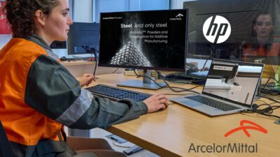 ArcelorMittal und HP arbeiten an der Entwicklung neuer Stahlmaterialien für den 3D-Druck mit Binder-Jetting-Technologie. Mitarbeiterin von ArcelorMittal am Computer, der eine Präsentation zur Optimierung von Stahlpulver für den 3D-Druck zeigt, daneben ein Laptop mit HP Metal Jet Drucker.