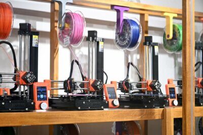 Prusa Mini-Drucker in der 3D-Druck-Ausstellung bei Esplora mit Fokus auf Nachhaltigkeit und Bildung Mehrere Prusa Mini 3D-Drucker in der Esplora-Ausstellung, die den 3D-Druckprozess mit nachhaltigem PLA-Filament aus recyceltem Plastik zeigen