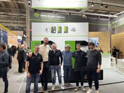 One Click Metal und Magù präsentieren schwarzes Titan für 3D-Druck in der Schmuckindustrie Team von One Click Metal und Magù auf einer Messe, Einführung von schwarzem Titan für den 3D-Druck in der Schmuckherstellung