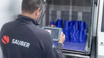 Mitarbeiter von Sauber Motorsport bedient die C1 Max von AM Solutions zur Nachbearbeitung von SLA-Druckteilen mit verbessertem Zeit- und Gesundheitsmanagement