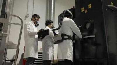 Elektronenstrahl-Pulverbett-Fusionssystem im Einsatz im MSAM-Labor der Universität Waterloo Drei Personen in Laborkitteln arbeiten an einem Elektronenstrahl-Pulverbett-Fusionssystem im MSAM-Labor der Universität Waterloo