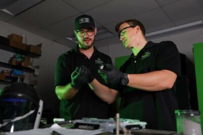Montana Tech Studierende mit 3D-Druck-Komponenten im Labor Zwei Studierende der Montana Technological University analysieren 3D-gedruckte Bauteile in einem Labor für additive Fertigung