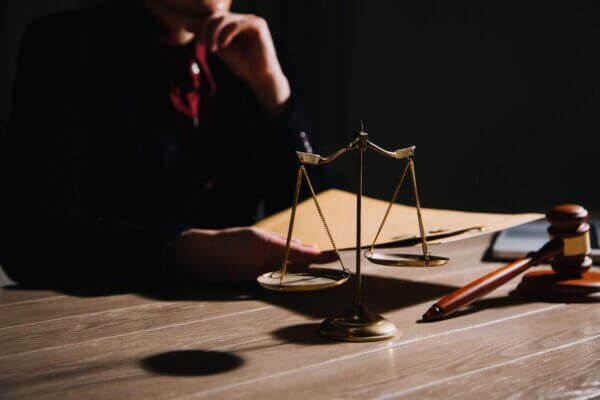 Symbolbild zu einem Rechtsstreit: Waage und Richterhammer auf einem Schreibtisch, thematisch passend zur Fusion von Desktop Metal und Nano Dimension.