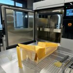 Additiv gefertigtes Werkzeug, produziert mit Stratasys F900, auf einer Werkbank mit offener Druckkammer.