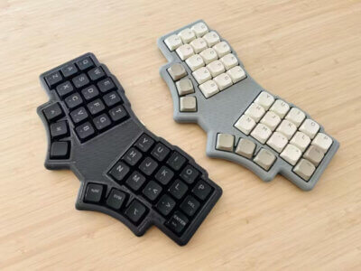 Zwei LoremIpsum36-Keyboards mit ergonomischer Tastenanordnung, 3D-gedrucktem Gehäuse und mechanischen Schaltern auf einem Holzschreibtisch