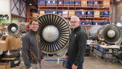 Tronosjet und Renishaw: 3D-gedruckte Titan-Bauteile für die Luftfahrt mit FAA-Zertifizierung Ingenieure von Tronosjet Manufacturing vor Flugzeugtriebwerken in einer Produktionshalle, arbeiten an 3D-gedruckten Titan-Bauteilen für die Luftfahrt