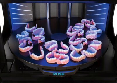 3D-gedruckte Zahnprothesen mit Stratasys TrueDent-Technologie in Europa Mehrere 3D-gedruckte Zahnprothesen auf Druckplattform eines Stratasys-Druckers in Dentalanwendung