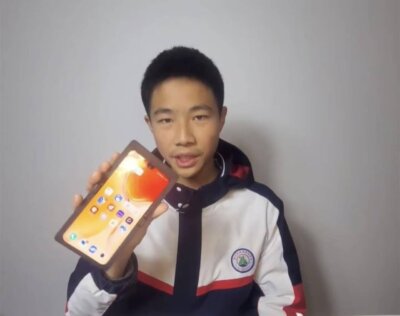 Chinesischer Schüler Lan Bowen zeigt sein mit einem 3D-Drucker erstelltes faltbares Smartphone Lan Bowen hält ein selbstgebautes faltbares Smartphone in der Hand, das aus 3D-gedruckten Teilen und alten Handy-Komponenten besteht