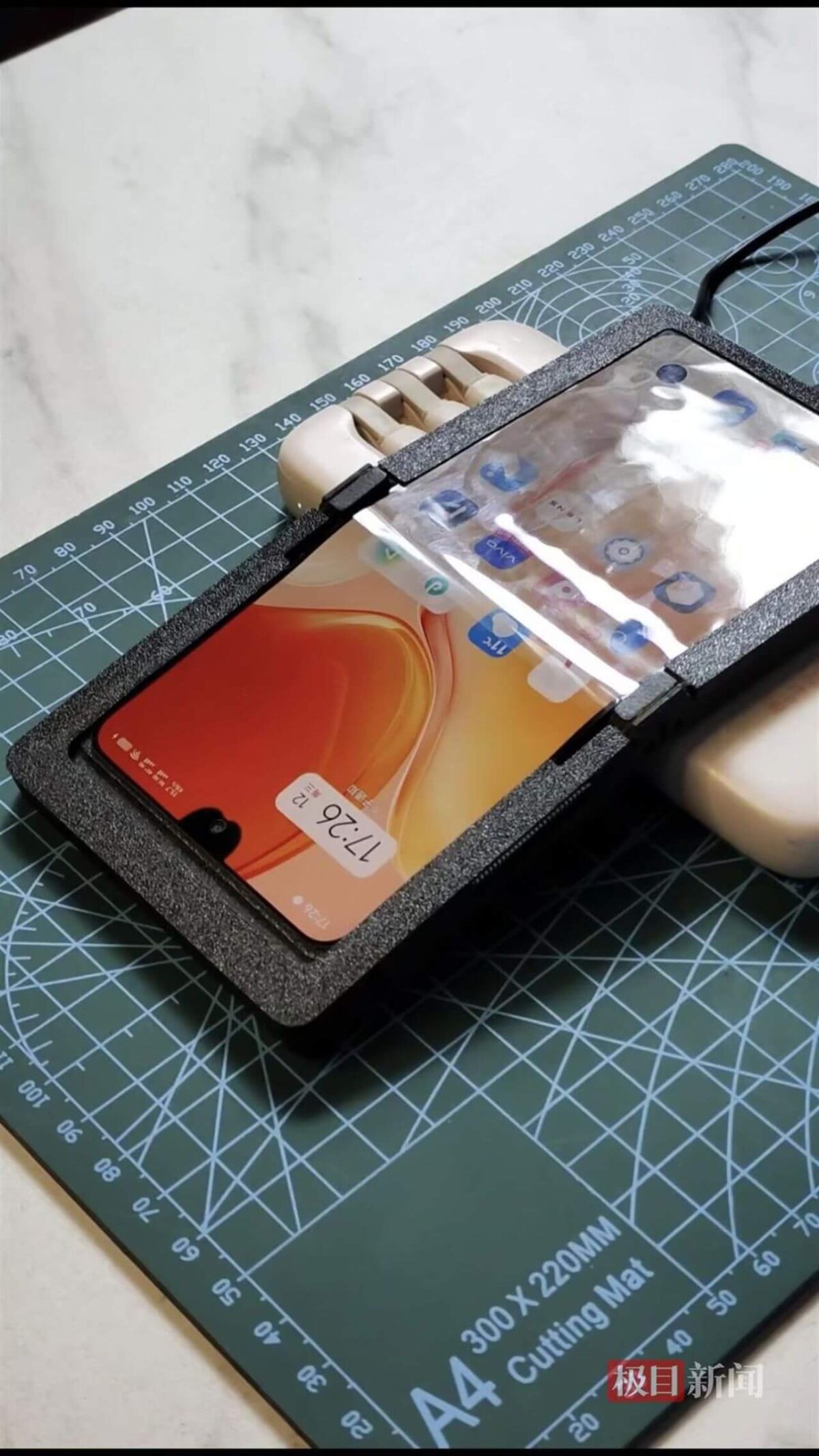 Ein von Lan Bowen selbstgebautes faltbares Smartphone mit 3D-gedrucktem Gehäuse liegt auf einer Schneidematte