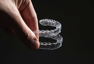 Eine Hand hält zwei transparente, thermoformbare Aligner aus dem neuen Material Lucentra™ für die Kieferorthopädie