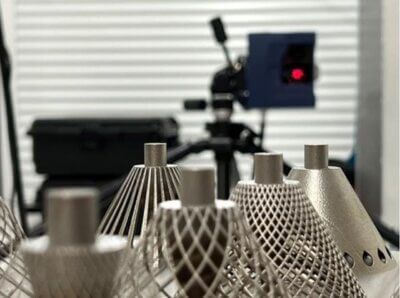 3D-gedruckte Metallbauteile aus dem Projekt Ad-Proc-Add II zur hybriden Fertigung 3D-gedruckte Metallbauteile mit Gitterstruktur vor einem Messsystem im Rahmen des Projekts Ad-Proc-Add II