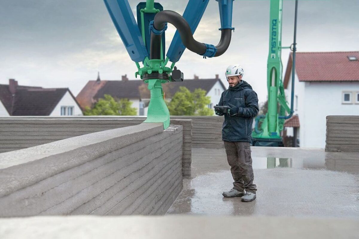 Ein Bauarbeiter steuert den mobilen 3D-Drucker Instatiq P1, der auf der Baustelle tragende Wände aus Normbeton druckt