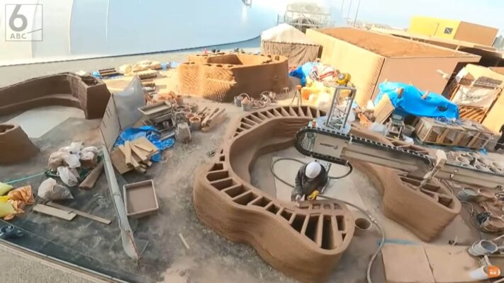 3D-Druck eines organisch geformten Lehmbauwerks für die Expo 2025 in Osaka Baustelle mit 3D-Drucker, der eine geschwungene Lehmbauwand für eine Toilettenanlage auf der Expo 2025 in Osaka fertigt