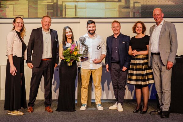 Preisträger der 3D Pioneers Challenge 2025 mit Trophäe für das 3D-gedruckte Herz auf der Bühne der rapid.tech 3D