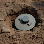 Teilweise eingegrabene Panzerabwehrmine in sandigem Boden, symbolisiert Einsatz von 3D-Drucktechnik im Ukrainekrieg