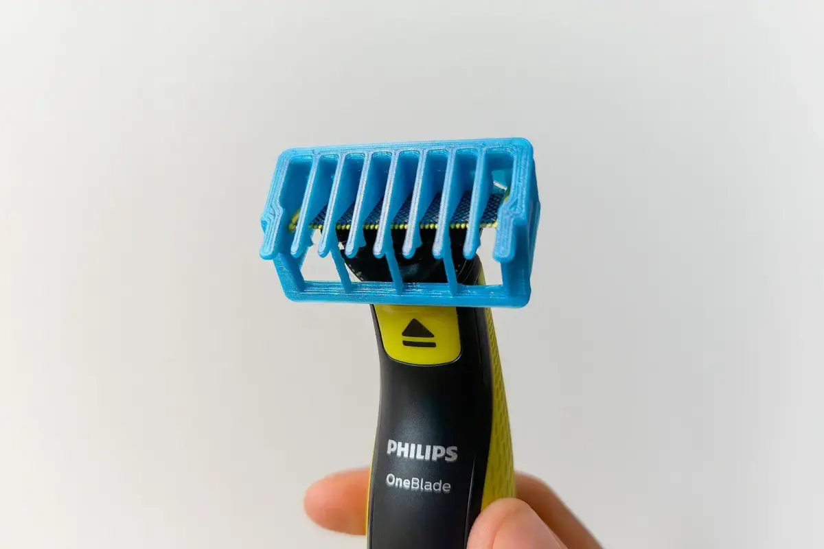 Nahaufnahme eines Philips OneBlade Rasierers mit montiertem blauem 3D-gedrucktem Kammaufsatz