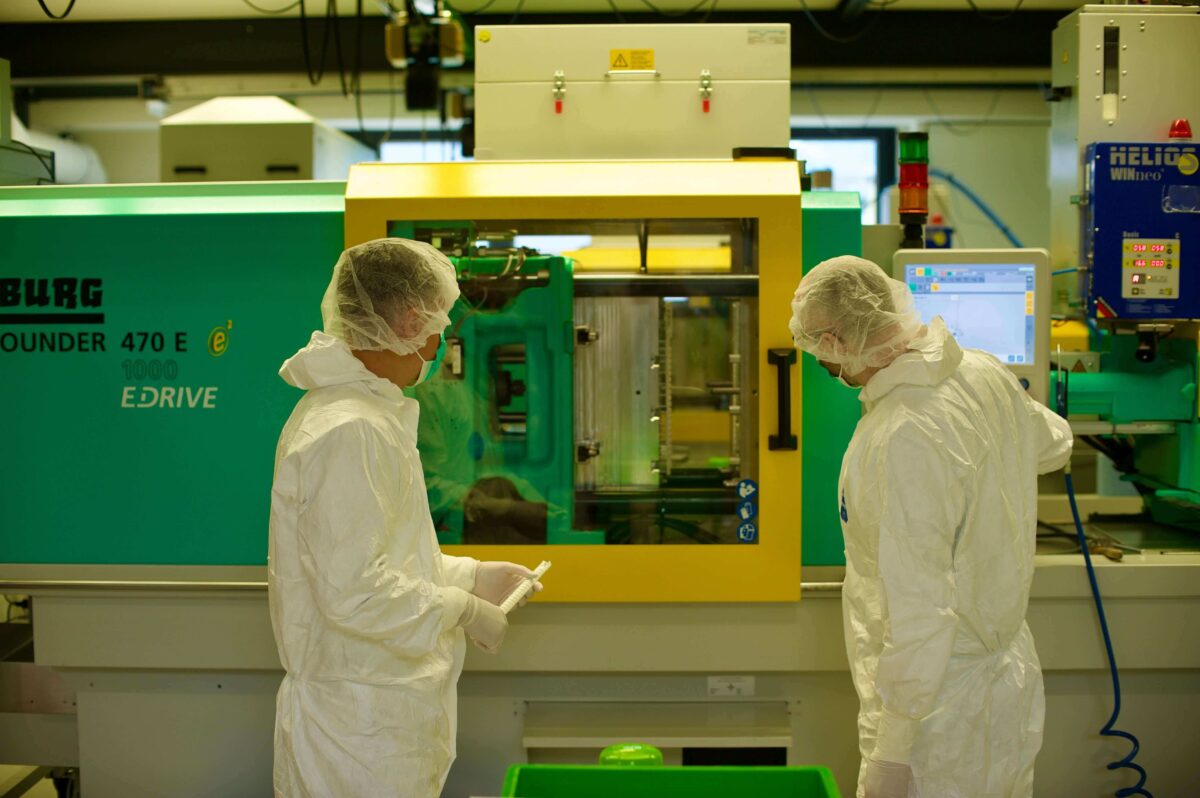 Mitarbeitende im Reinraum fertigen Spritzgussteile für MEDIRA-Einführsystem an moderner Arburg-Maschine