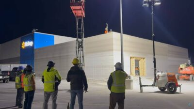 Bauarbeiter beobachten den 3D-Druck eines Supermarkt-Anbaus bei Nacht auf dem Parkplatz eines Walmart-Marktes in Huntsville