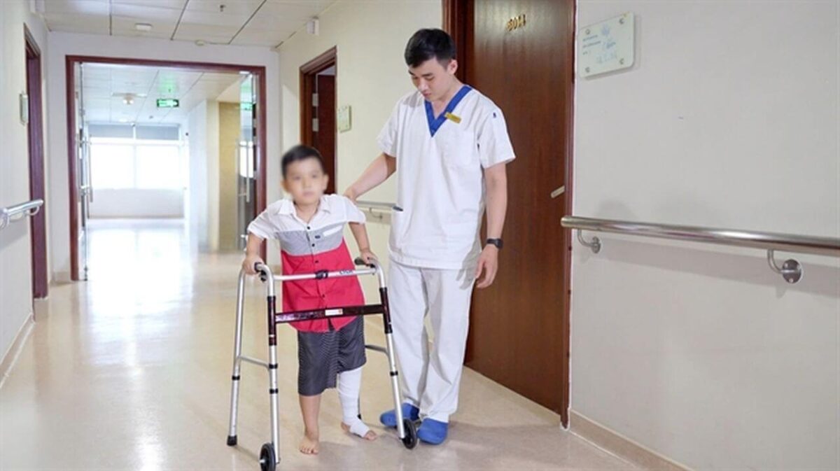 Achtjähriger Junge mit Gehwagen beim Reha-Training nach 3D-gedrucktem Femurimplantat in vietnamesischem Krankenhaus