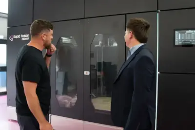 Techniker inspizieren den Hybrid-3D-Drucker Medusa von Rapid Fusion vor dem geplanten Serienstart 2026 Zwei Personen betrachten den Medusa Hybrid-3D-Drucker von Rapid Fusion in einer Produktionsumgebung
